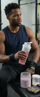 Male athlete in a gym setting using an unbranded shaker bottle for pre-workout